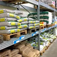 Hyllor fyllda med säckar av kalkputs inomhus. Material för byggprojekt redo att användas.