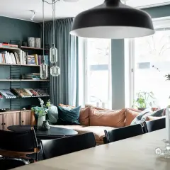 Mysigt vardagsrum med en soffa i mockaimitation, bokhylla och en matplats. En känsla av ett renoverat hus från 50-talet.