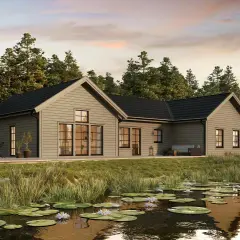 Modernt hus med brun fasad vid en näckrosdamm, omgivet av skog.