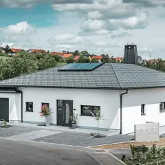Vitt modernt hus med garage och solpaneler på ett vinklat sadeltak.