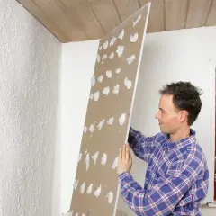 Man förbereder för att limma gipsskivor på en vägg.