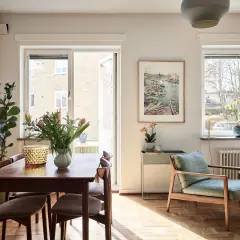 Vardagsrum med matplats i ett 20-tals hus arkitektur. Solstrålar lyser upp trägolvet och möblerna.