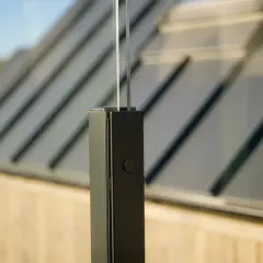Detalj av stolpe för att bygga vindskydd altan. Glasparti med mörk stolpe och en knapp.