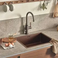 Köksbänk med diskho och blandare. Bänkskivan i gråmelerad sten ser ut att vara polerad kalksten, perfekt för en köksmiljö.