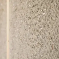Närbild på ekologisk isolering, ett material med synlig textur av fibrer och små partiklar, inramat av trä.