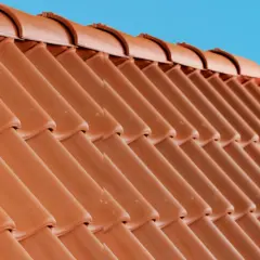 Detaljerad vy av en tegeltak konstruktion mot en klarblå himmel.