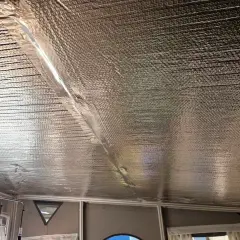 Isolera tak underifrån med silverfärgad bubbelplast. En tejpad skarv löper diagonalt över taket.