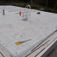Grundläggning för att bygga attefallshus med isolering, rördragning och armeringsjärn. En såg ligger på isoleringen.