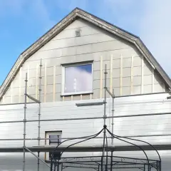 Hus med ställningar och påbörjat byte av eternit fasad.