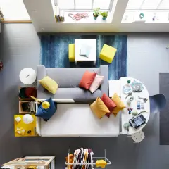 Litet tv rum inspiration med grå soffa, färgglada kuddar, blå matta och gula detaljer.