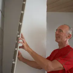 Man monterar en skiva med fästen, en smart alternativ till gipsskivor för väggar.