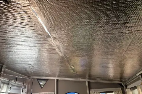 Isolera tak underifrån med silverfärgad bubbelplast. En tejpad skarv löper diagonalt över taket.
