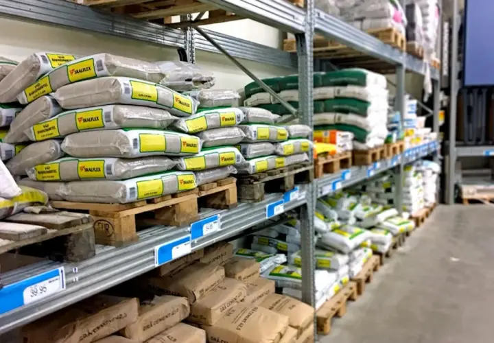 Hyllor fyllda med säckar av kalkputs inomhus. Material för byggprojekt redo att användas.