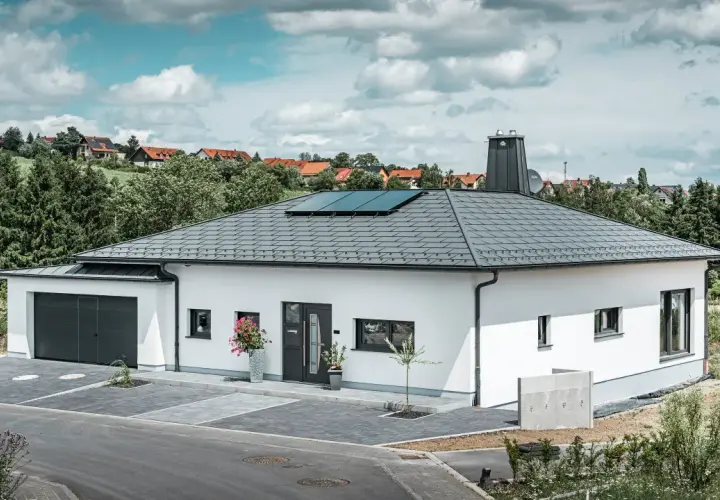 Vitt modernt hus med garage och solpaneler på ett vinklat sadeltak.