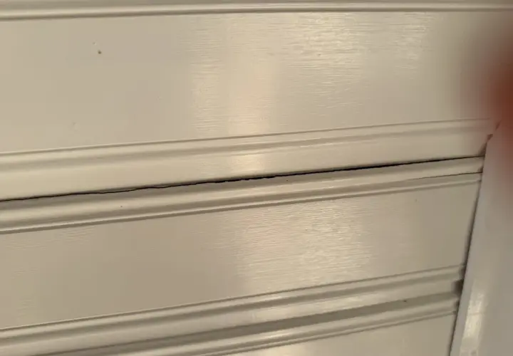 Detaljerad vy av vita träpaneler med synliga sprickor i taket.