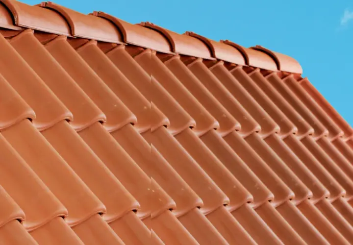 Detaljerad vy av en tegeltak konstruktion mot en klarblå himmel.
