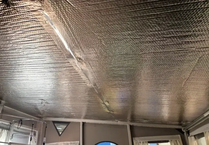 Isolera tak underifrån med silverfärgad bubbelplast. En tejpad skarv löper diagonalt över taket.