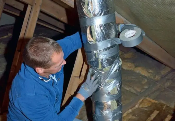 Man tejpar isolerad ventilationskanal i en friggebod.