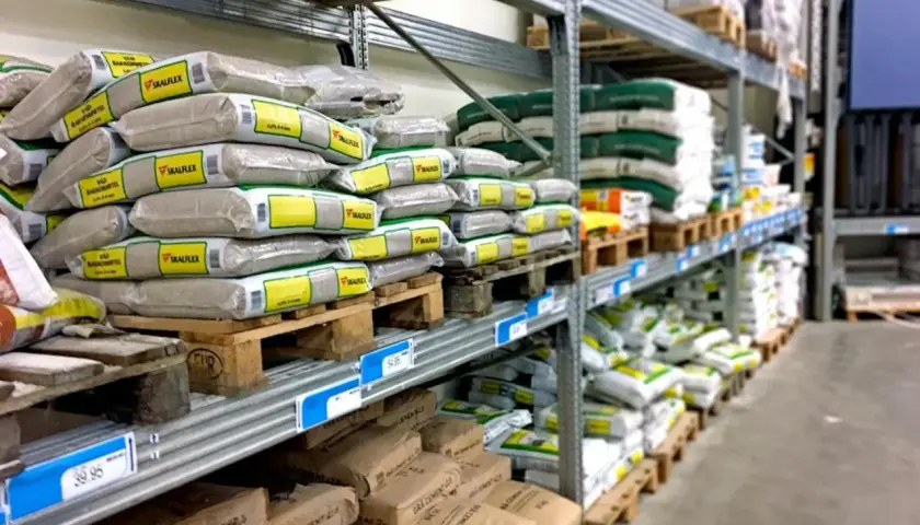 Hyllor fyllda med säckar av kalkputs inomhus. Material för byggprojekt redo att användas.