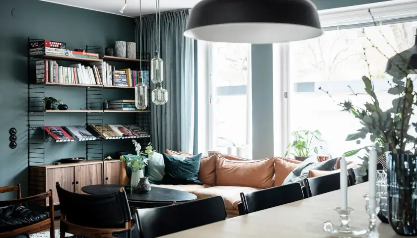 Mysigt vardagsrum med en soffa i mockaimitation, bokhylla och en matplats. En känsla av ett renoverat hus från 50-talet.
