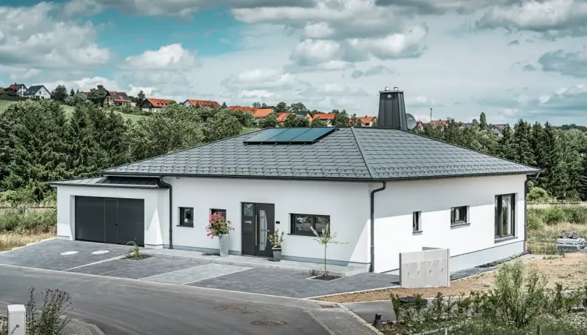 Vitt modernt hus med garage och solpaneler på ett vinklat sadeltak.
