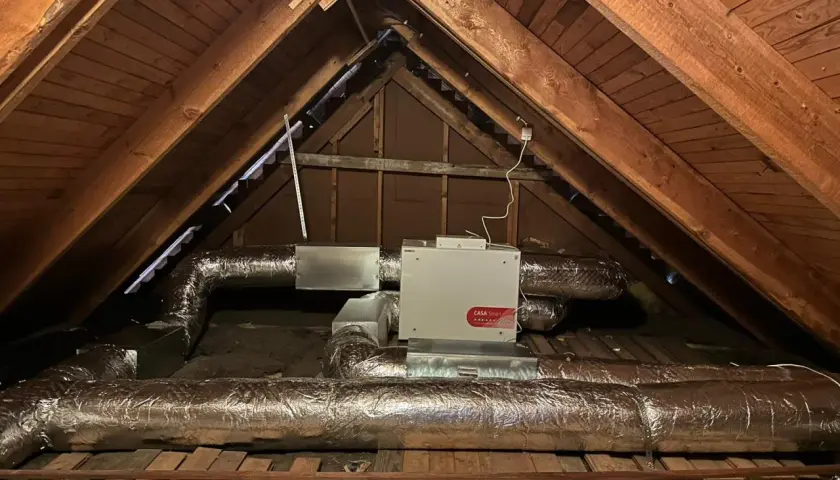 FTX-installation i en vind med isolerade ventilationsrör och en vit enhet märkt "CASA Smart".