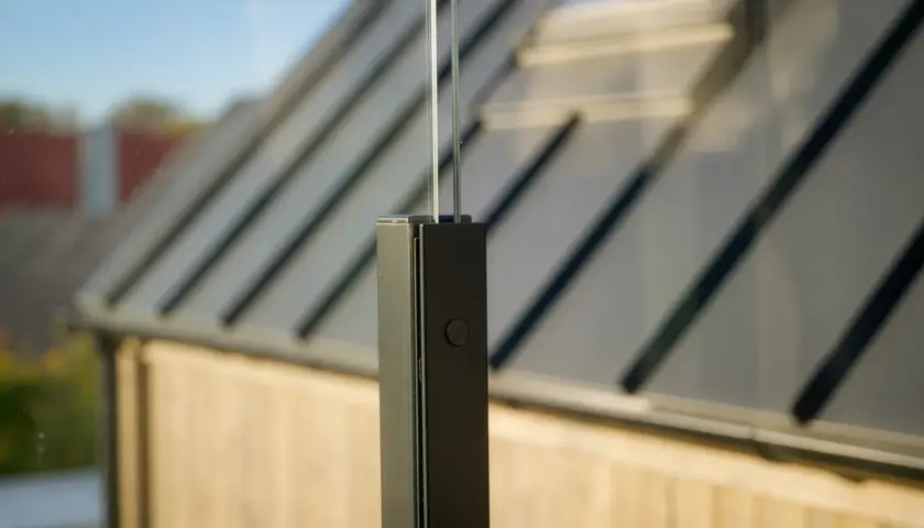 Detalj av stolpe för att bygga vindskydd altan. Glasparti med mörk stolpe och en knapp.