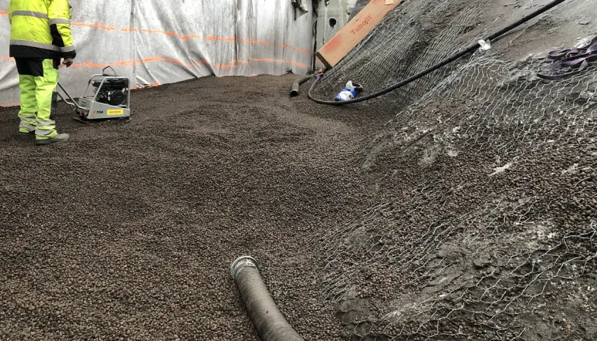 Arbetare packar lecakulor som isolering på en byggarbetsplats.