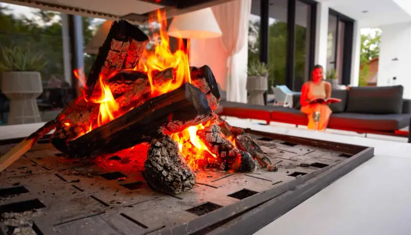 En kamin med sprakande eld. En kvinna läser en bok i bakgrunden. Perfekt för att installera kamin och njuta av värmen.