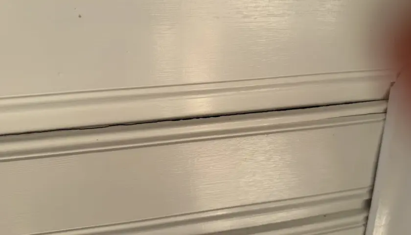 Detaljerad vy av vita träpaneler med synliga sprickor i taket.