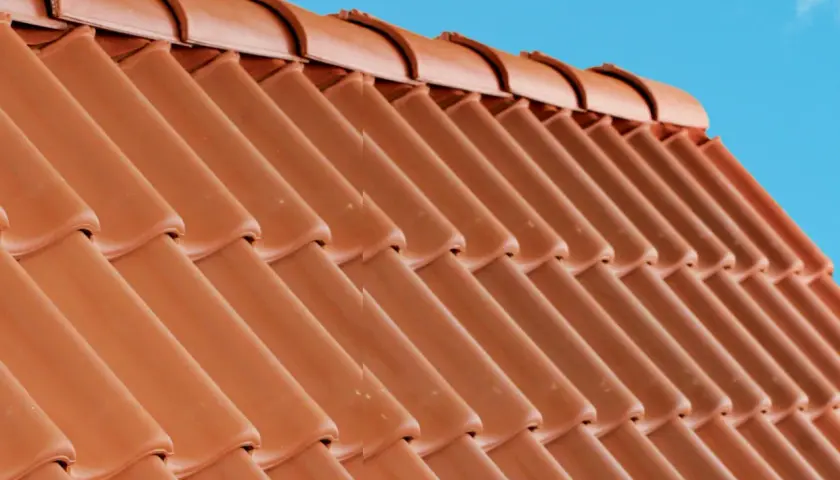 Detaljerad vy av en tegeltak konstruktion mot en klarblå himmel.