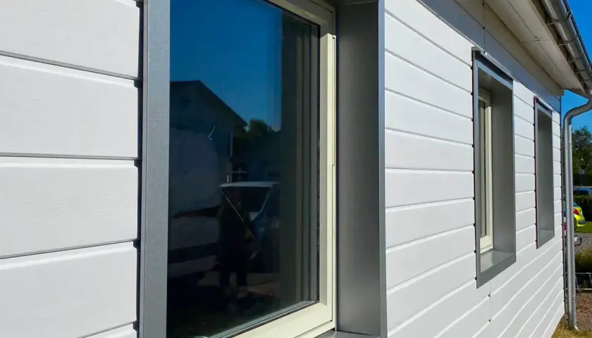 Vitt foder hus med fönster och takrännor.