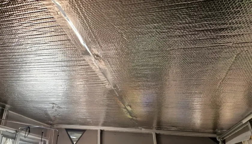 Isolera tak underifrån med silverfärgad bubbelplast. En tejpad skarv löper diagonalt över taket.