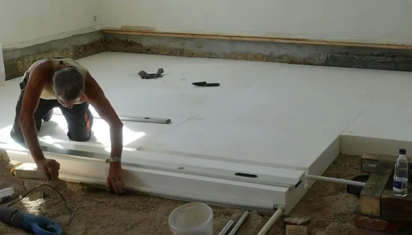 Man lägger isolering för att undvika kalla golv i krypgrund. Verktyg och material ligger utspridda.