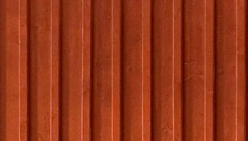En vägg av gammaldags lockpanel i faluröd färg. Träets ådring syns svagt under färgen.