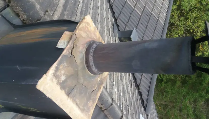 Skadad blyplåt 2mm runt skorstenen på ett tegeltak.