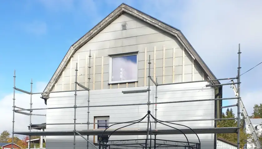 Hus med ställningar och påbörjat byte av eternit fasad.