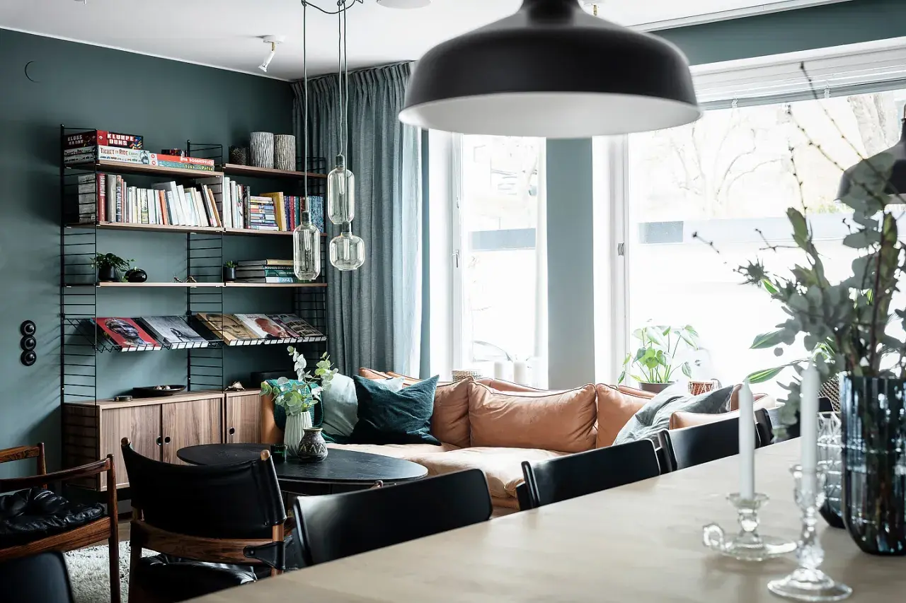 Mysigt vardagsrum med en soffa i mockaimitation, bokhylla och en matplats. En känsla av ett renoverat hus från 50-talet.