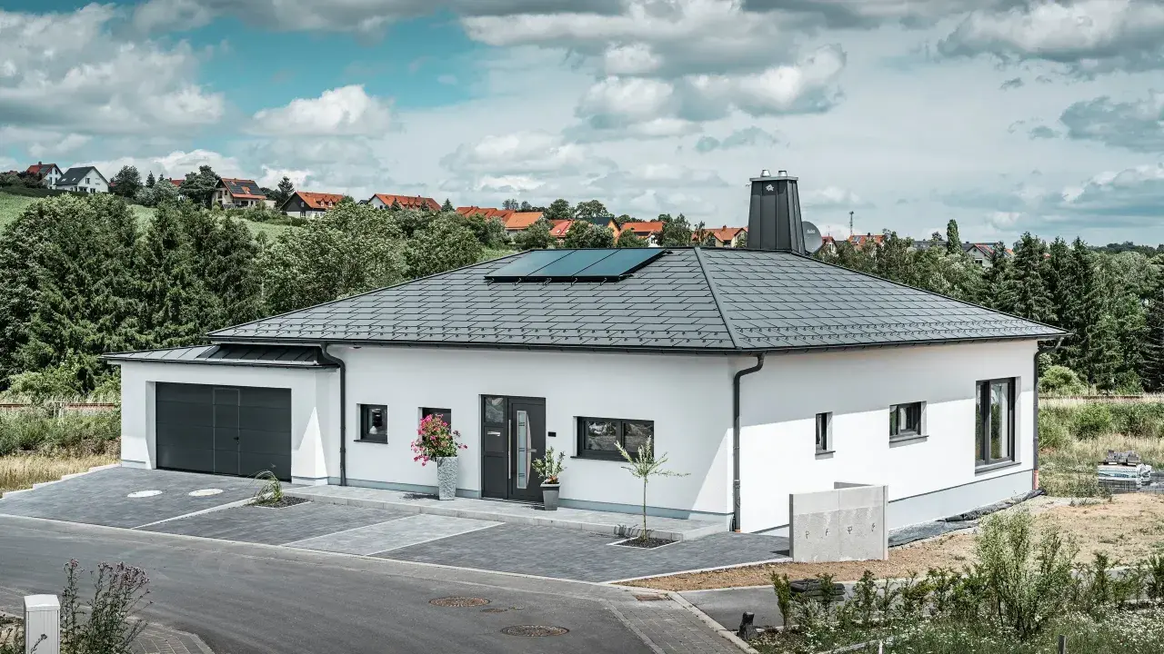 Vitt modernt hus med garage och solpaneler på ett vinklat sadeltak.