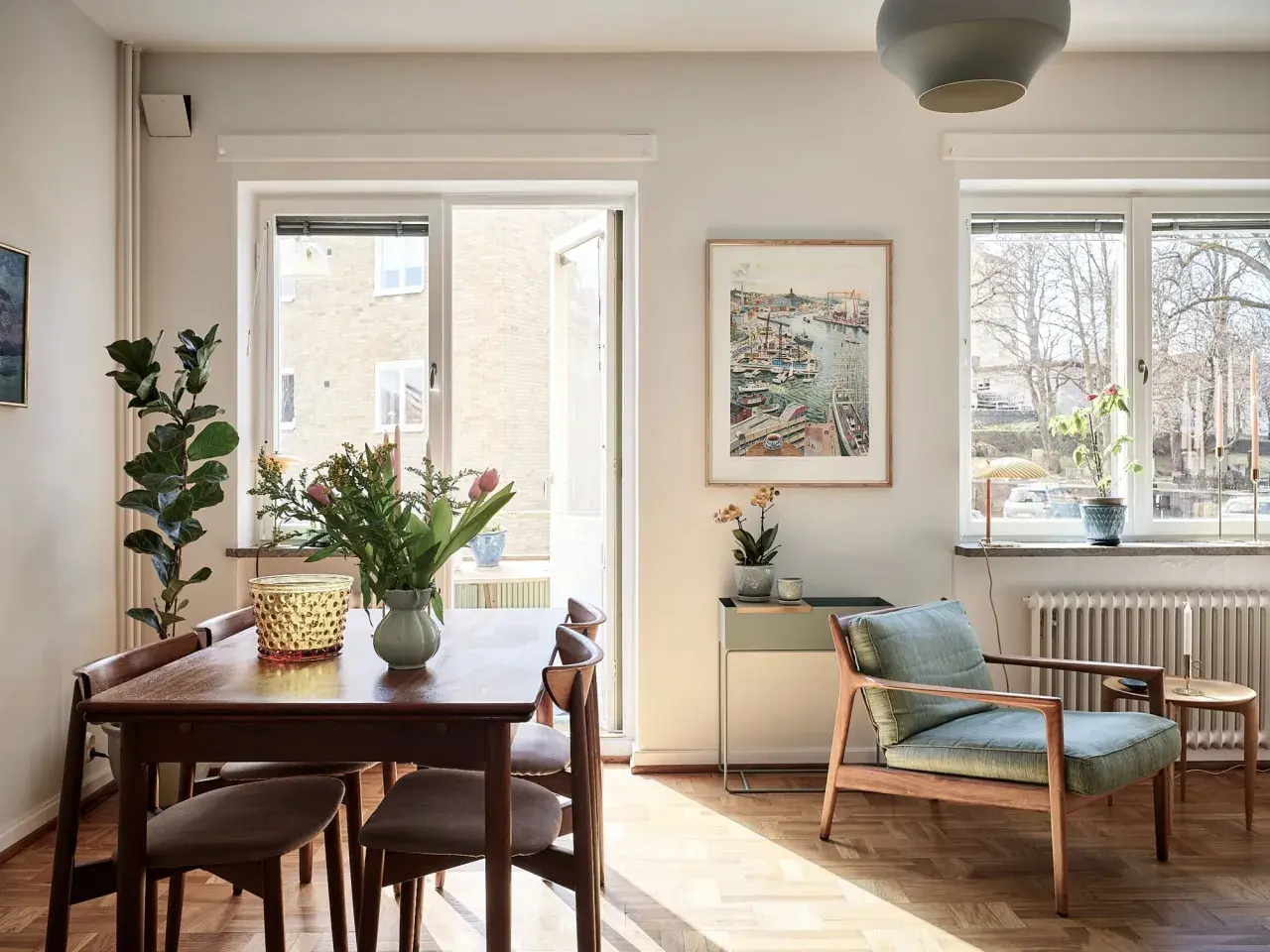 Vardagsrum med matplats i ett 20-tals hus arkitektur. Solstrålar lyser upp trägolvet och möblerna.