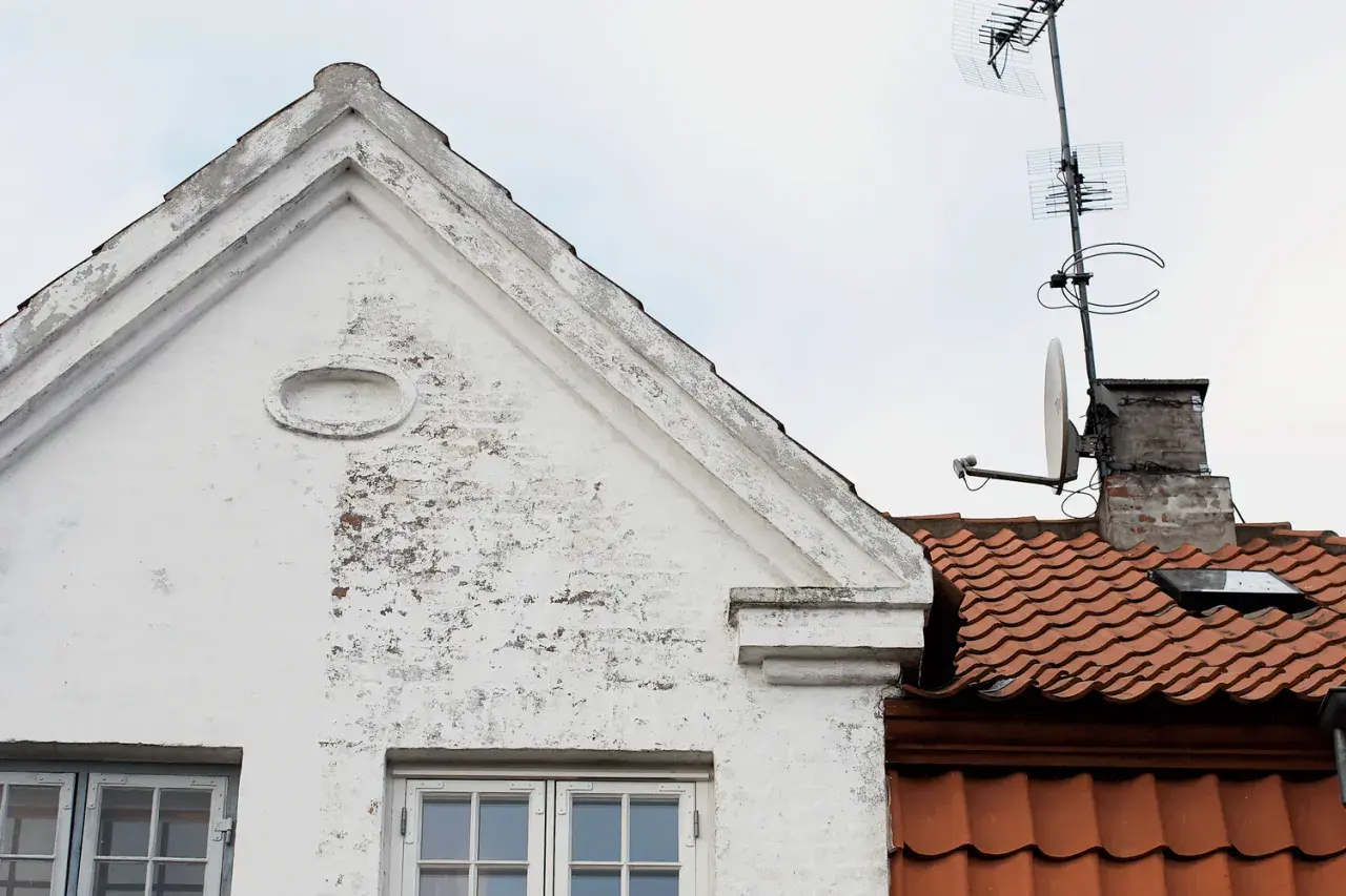 Vitt hus med tegeltak och antenner. Ett gammalt kc bruk som vittnar om svunna tider.