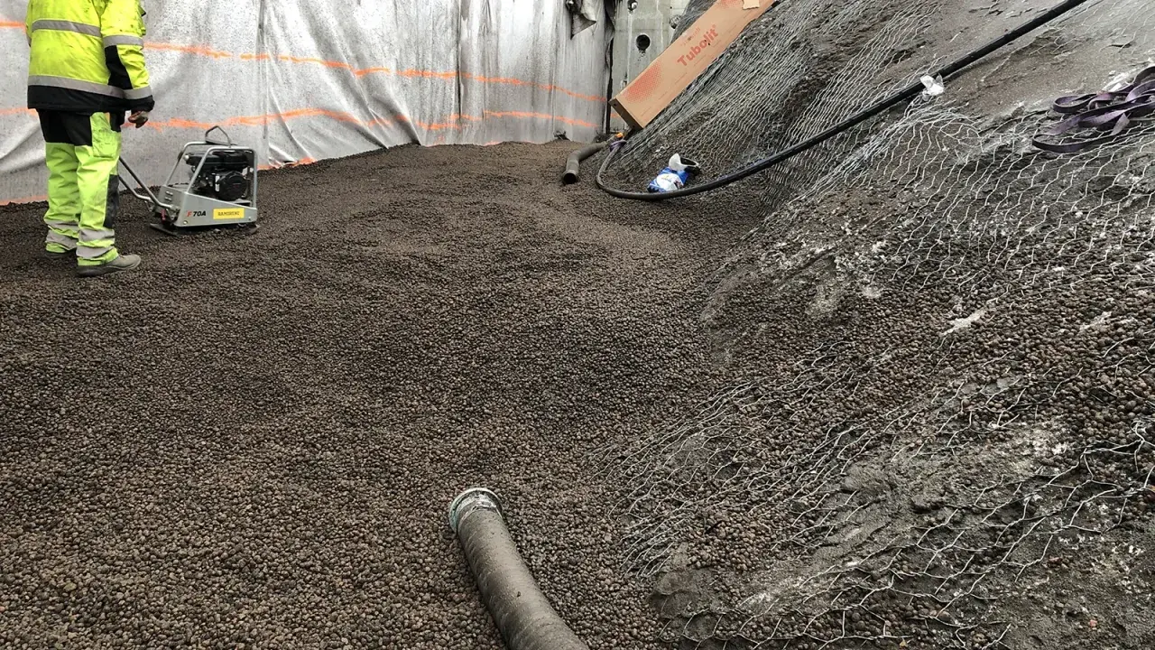Arbetare packar lecakulor som isolering på en byggarbetsplats.