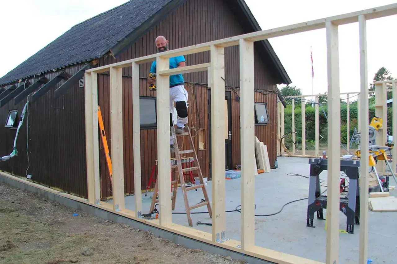 Man bygger ut huset, monterar trästomme på en byggarbetsplats.