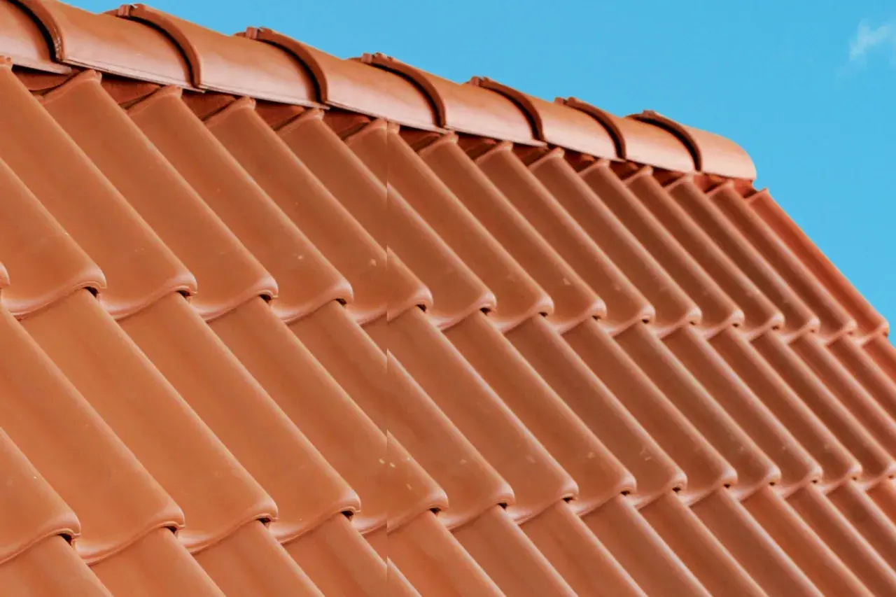Detaljerad vy av en tegeltak konstruktion mot en klarblå himmel.