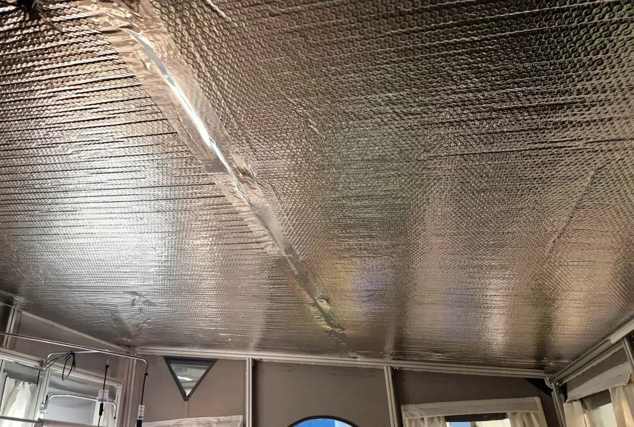 Isolera tak underifrån med silverfärgad bubbelplast. En tejpad skarv löper diagonalt över taket.