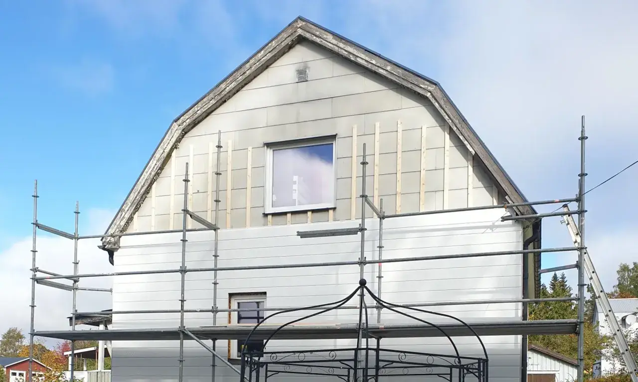Hus med ställningar och påbörjat byte av eternit fasad.