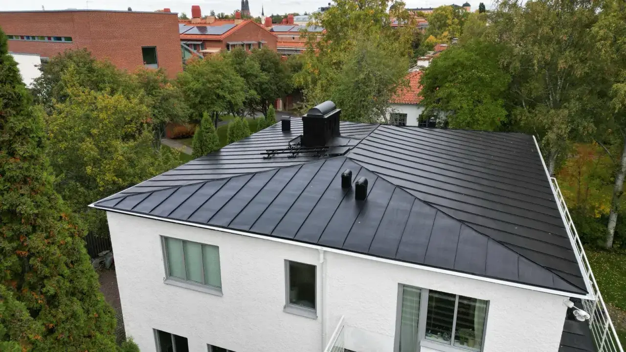 Svart pl&aring;ttak med skorsten och ventilationsr&ouml;r. Kanske aluzink nackdelar att beakta vid val av takmaterial.
