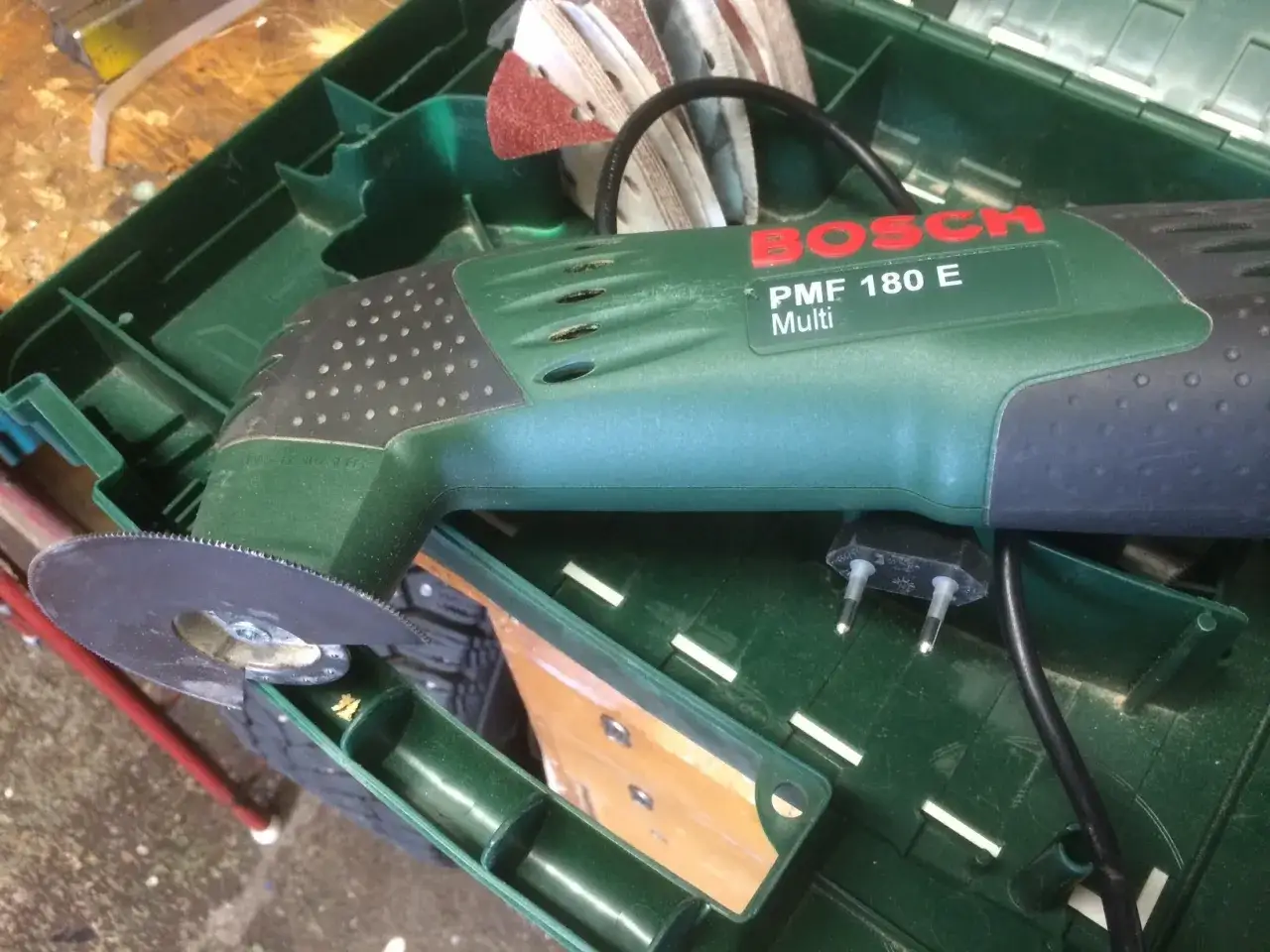 Bosch PMF 180 E multiverktyg med s&aring;gblad redo att kapa plasttak. Tillbeh&ouml;r som slippapper ligger i fodralet.