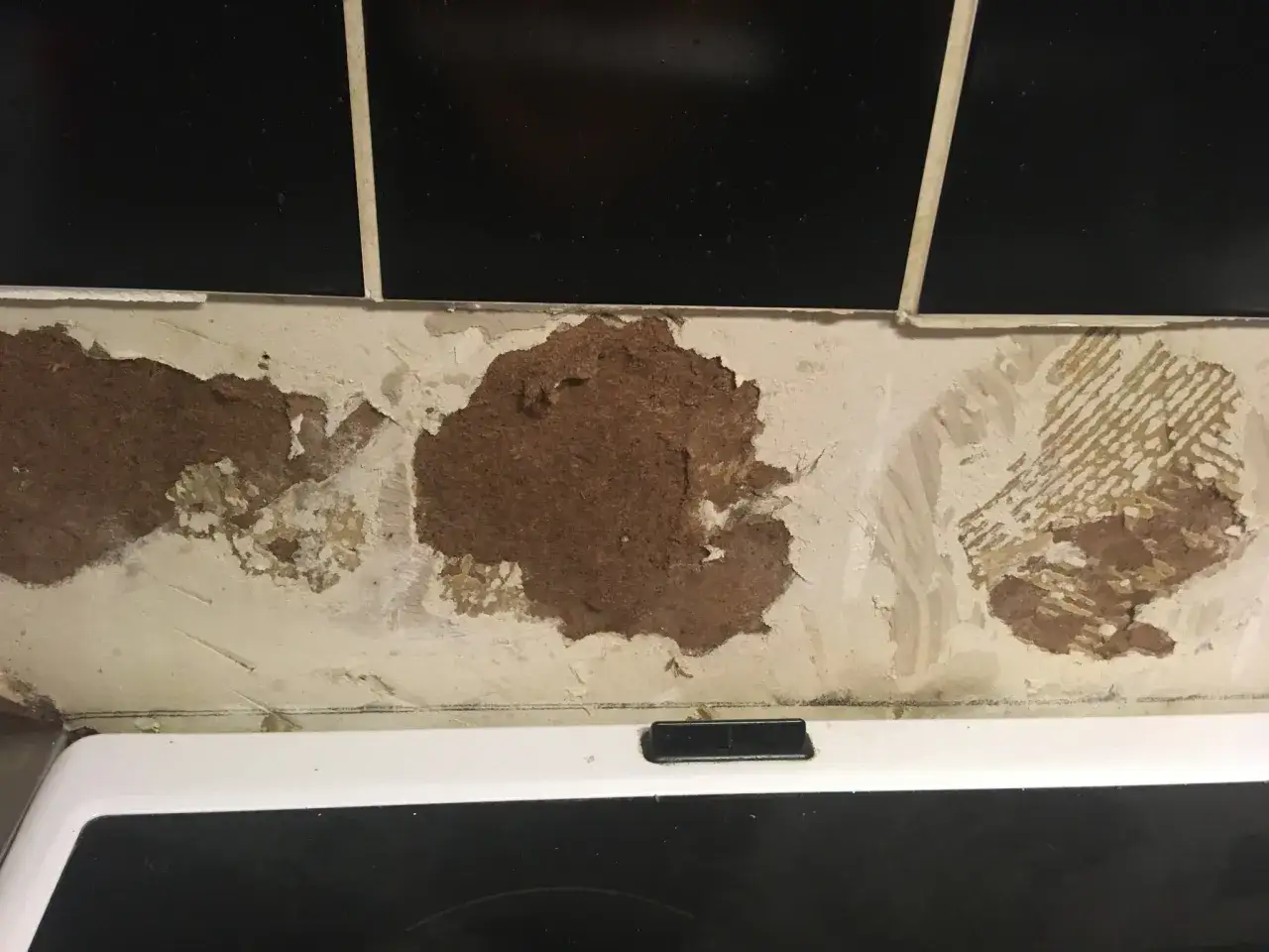 Skadad v&auml;gg d&auml;r kakel lossnat och blottar masonit.