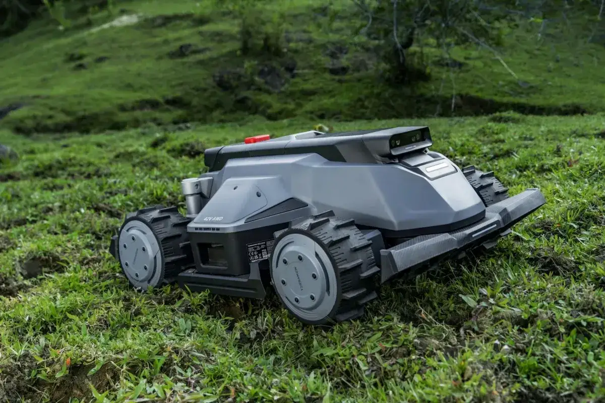 En Mammotion Luba 2 AWD 3000X robotgr&auml;sklippare med robusta hjul p&aring; en gr&ouml;n, kuperad gr&auml;smatta.